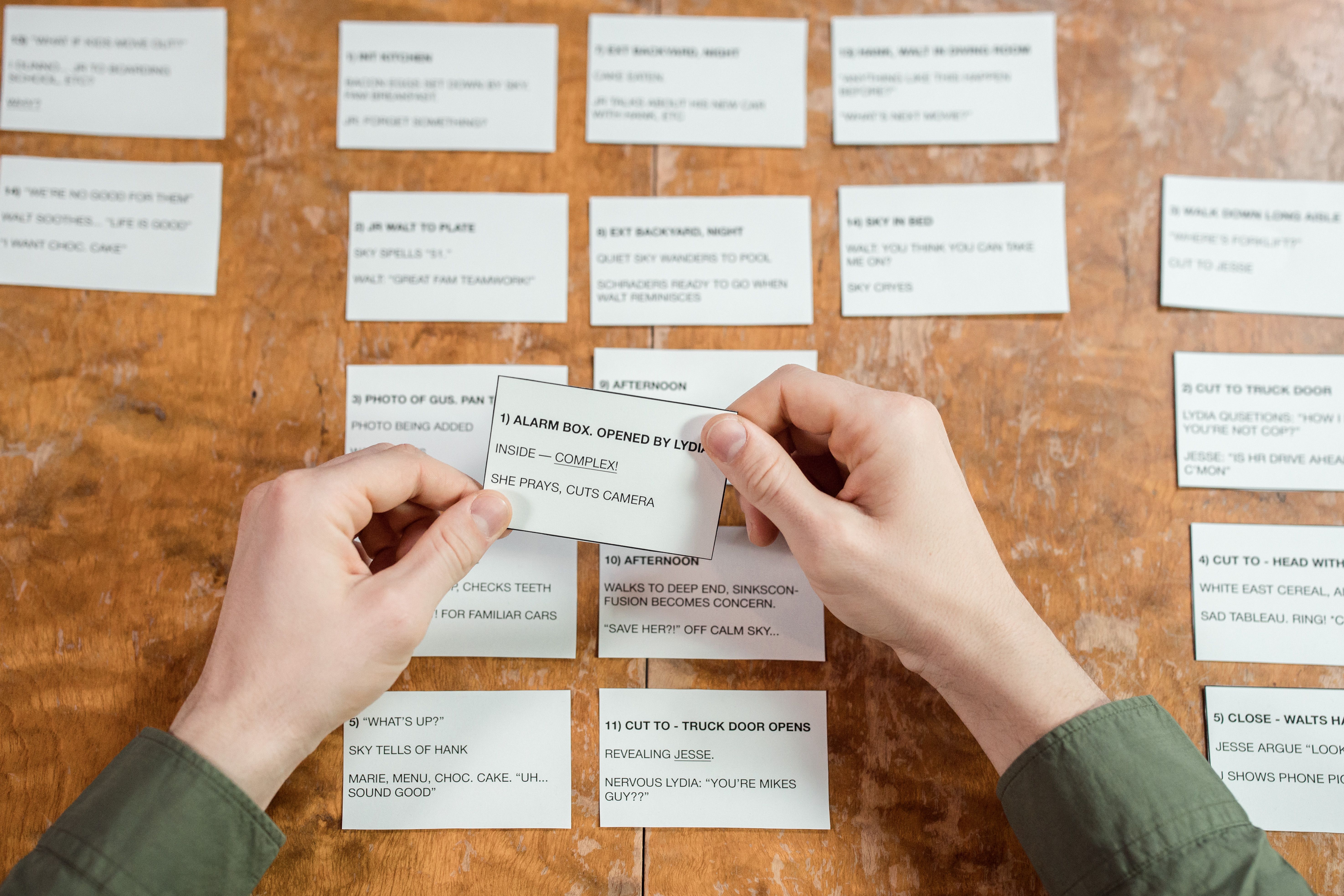 Hands organizing index cards on a desk to plan a sequence of work